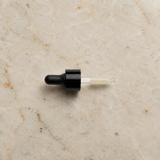 DermaReverse serum dropper filled with product, resting on a marble surface